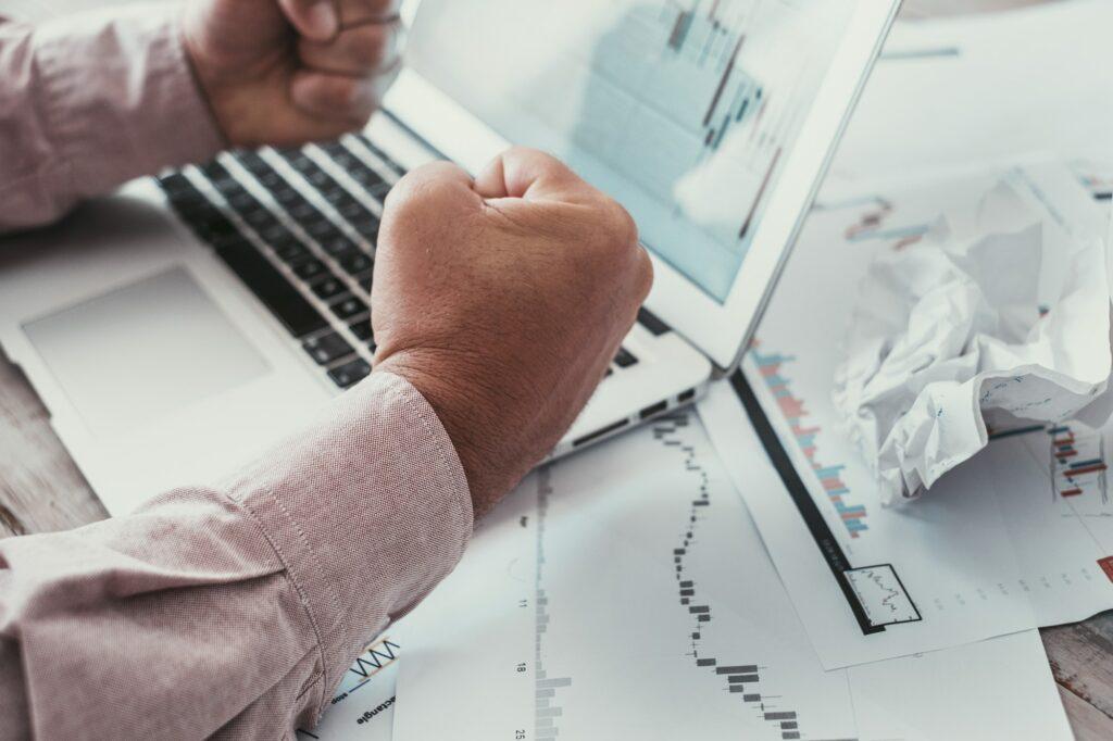 Close up of man punches against charts on paper and computer display. Concept of stock forex