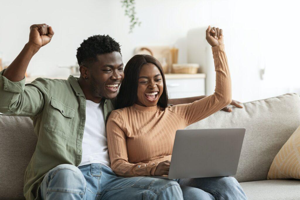 Lucky black couple trading together on Internet, home interior